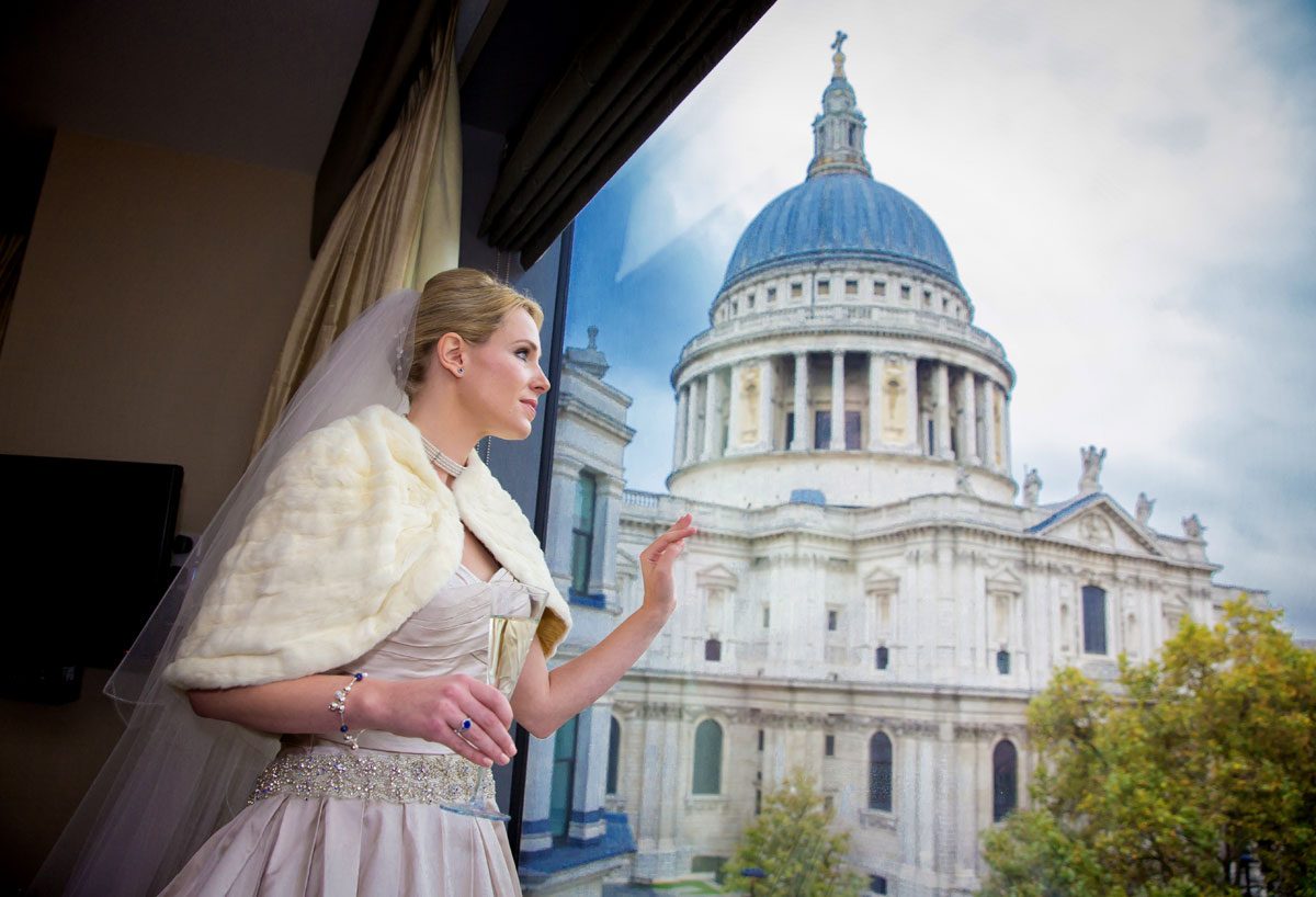 Bride looks from hotel window at St Pauls Cathedral on wedding day