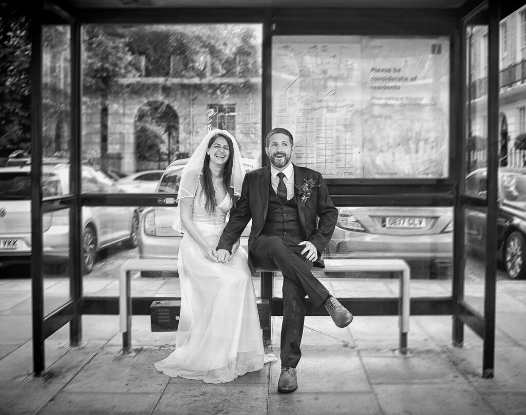 London-wedding-couple-pose-sat-in-bus stop