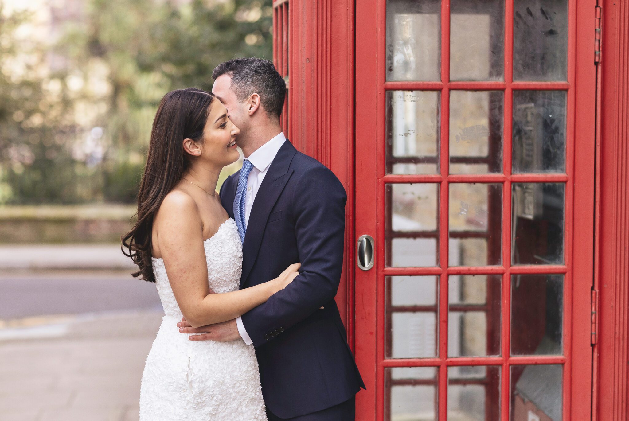 Bride and groom embrace by Chelsea phone box