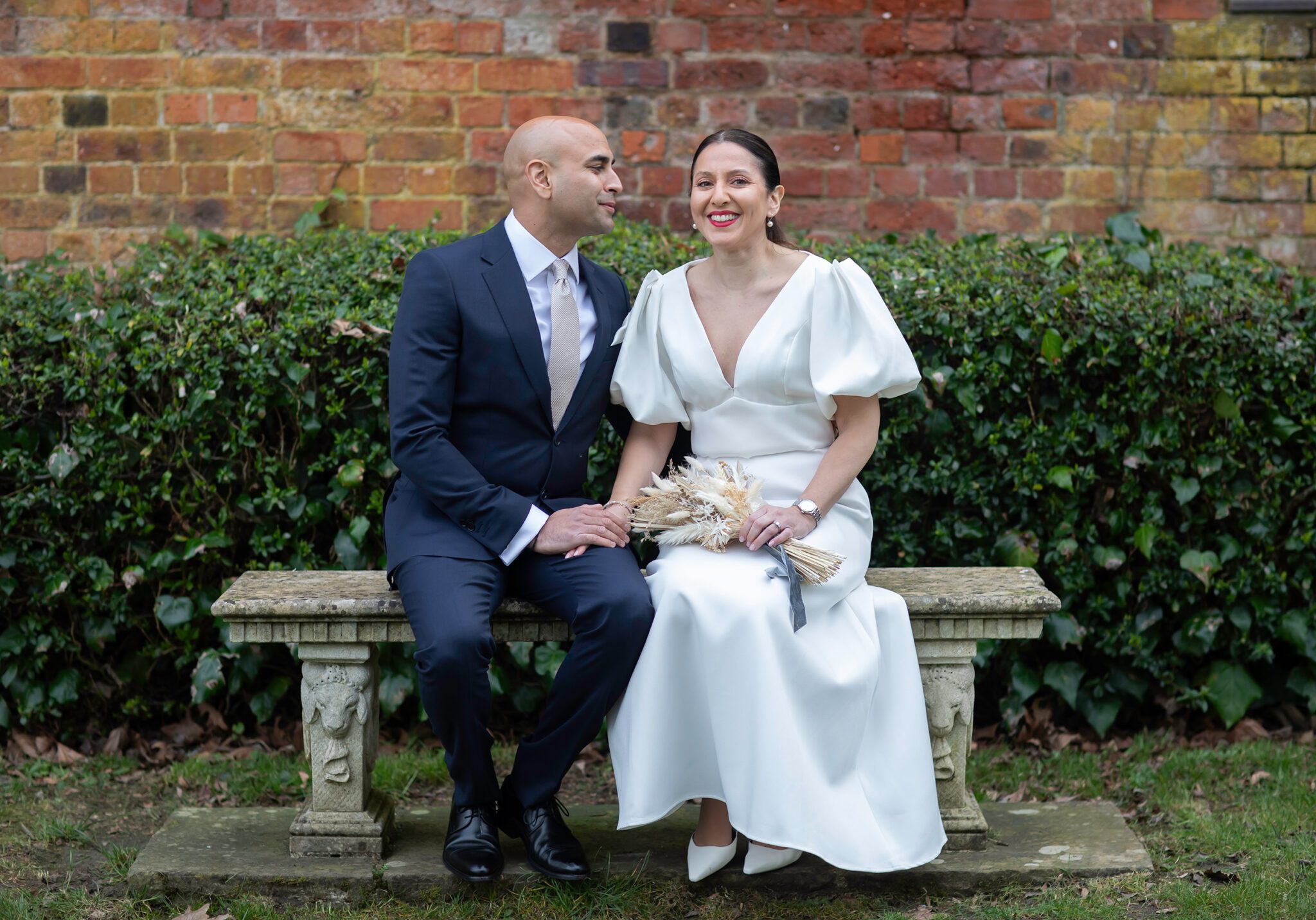Bride and groom sit on stone bench St Albans Registry wedding