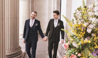 Two grooms hand in hand outside Old Marylebone Town Hall wedding
