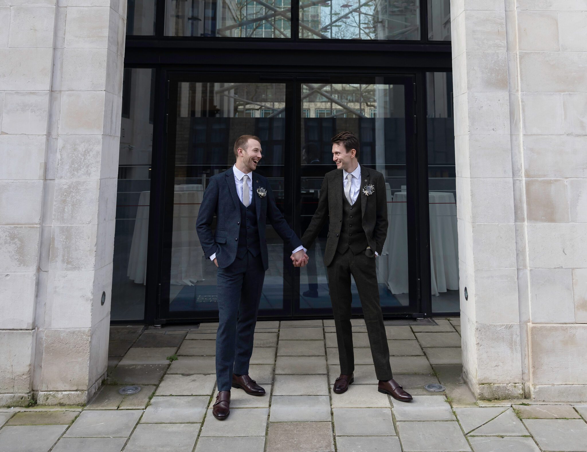 Two grooms hold hands Old Marylebone Town Hall wedding 