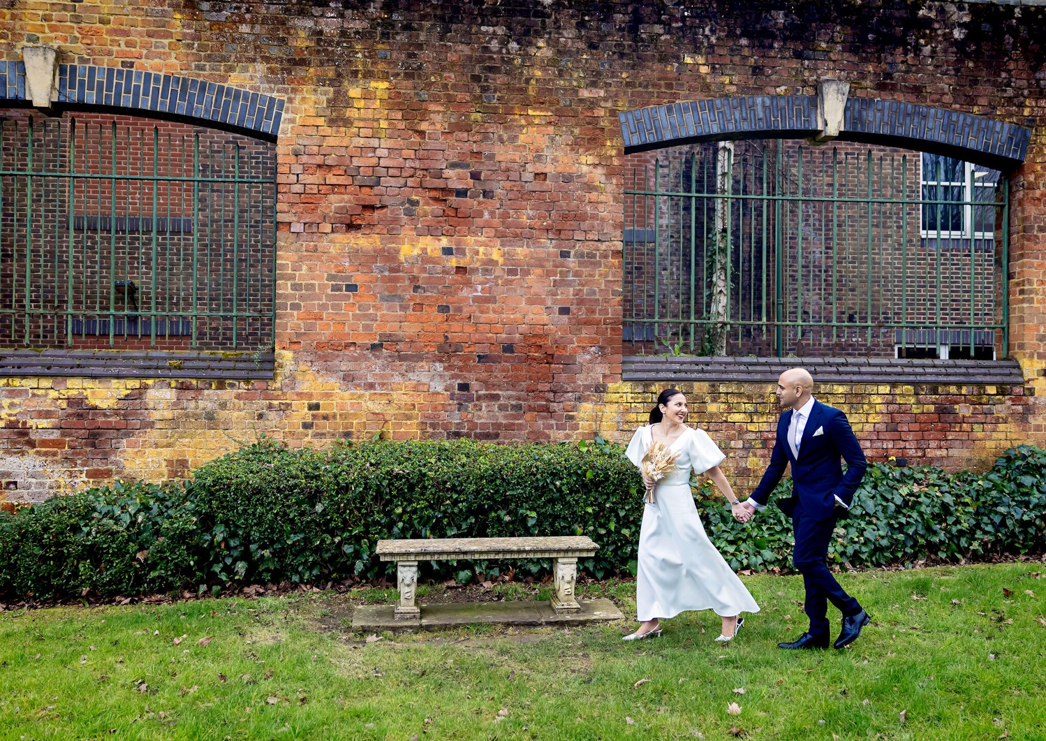Wedding couple walk past St Albans registry walls wide shot