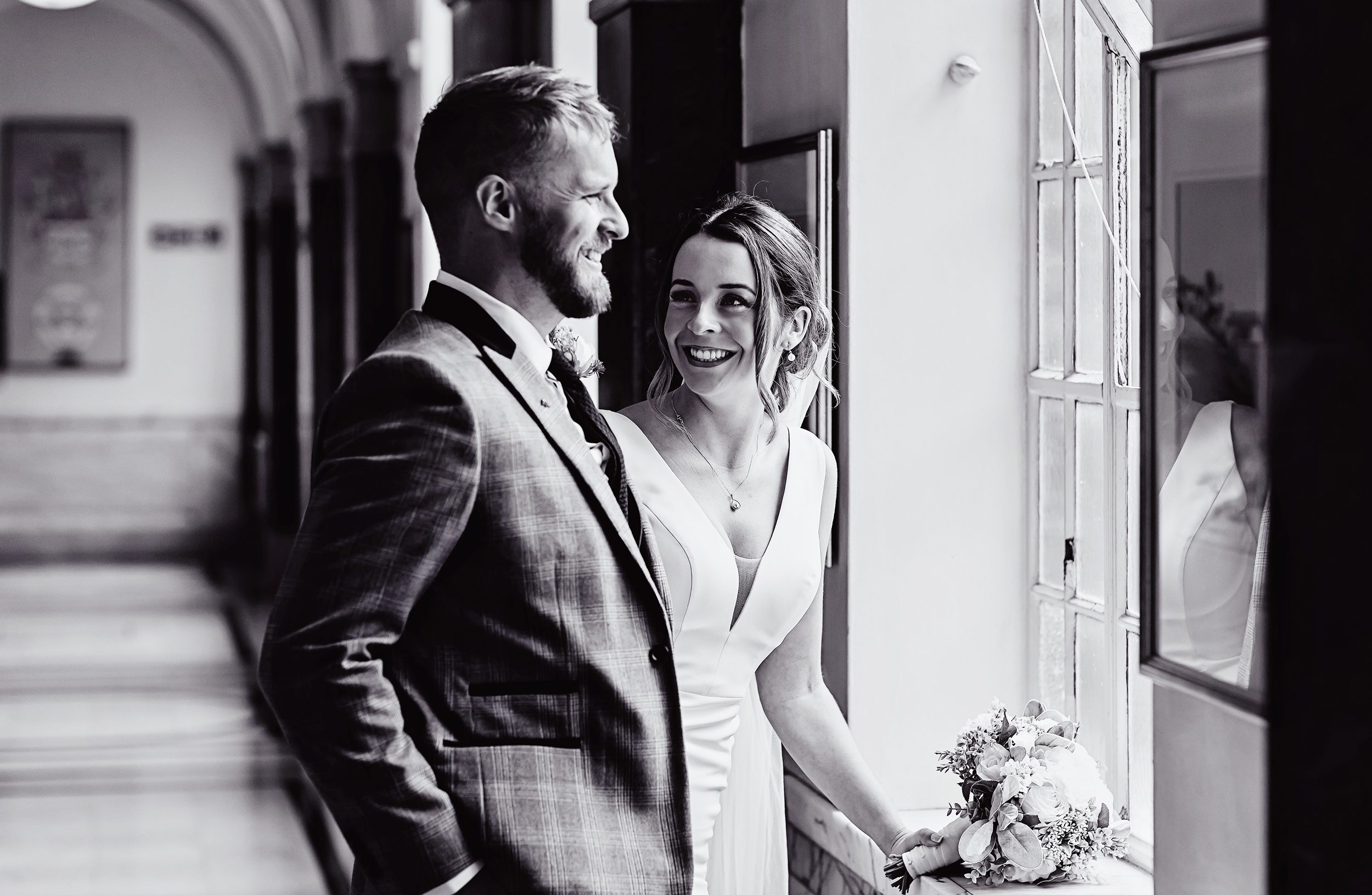 Islington Town Hall Wedding couple laugh together in corridor BW