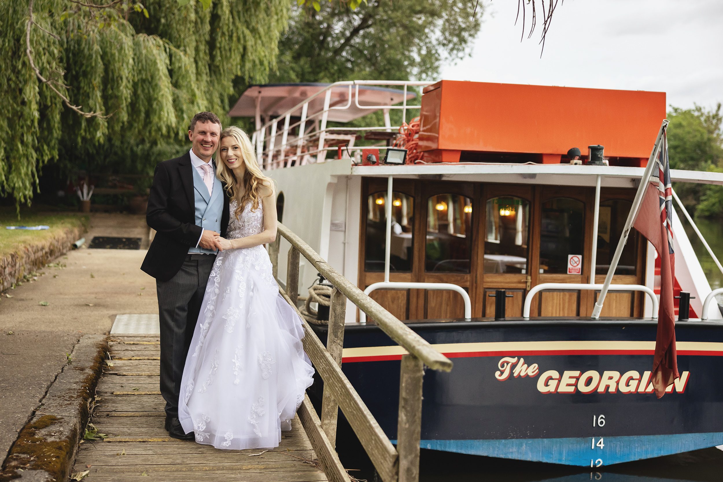 Bride and groom by wedding reception boat Windsor