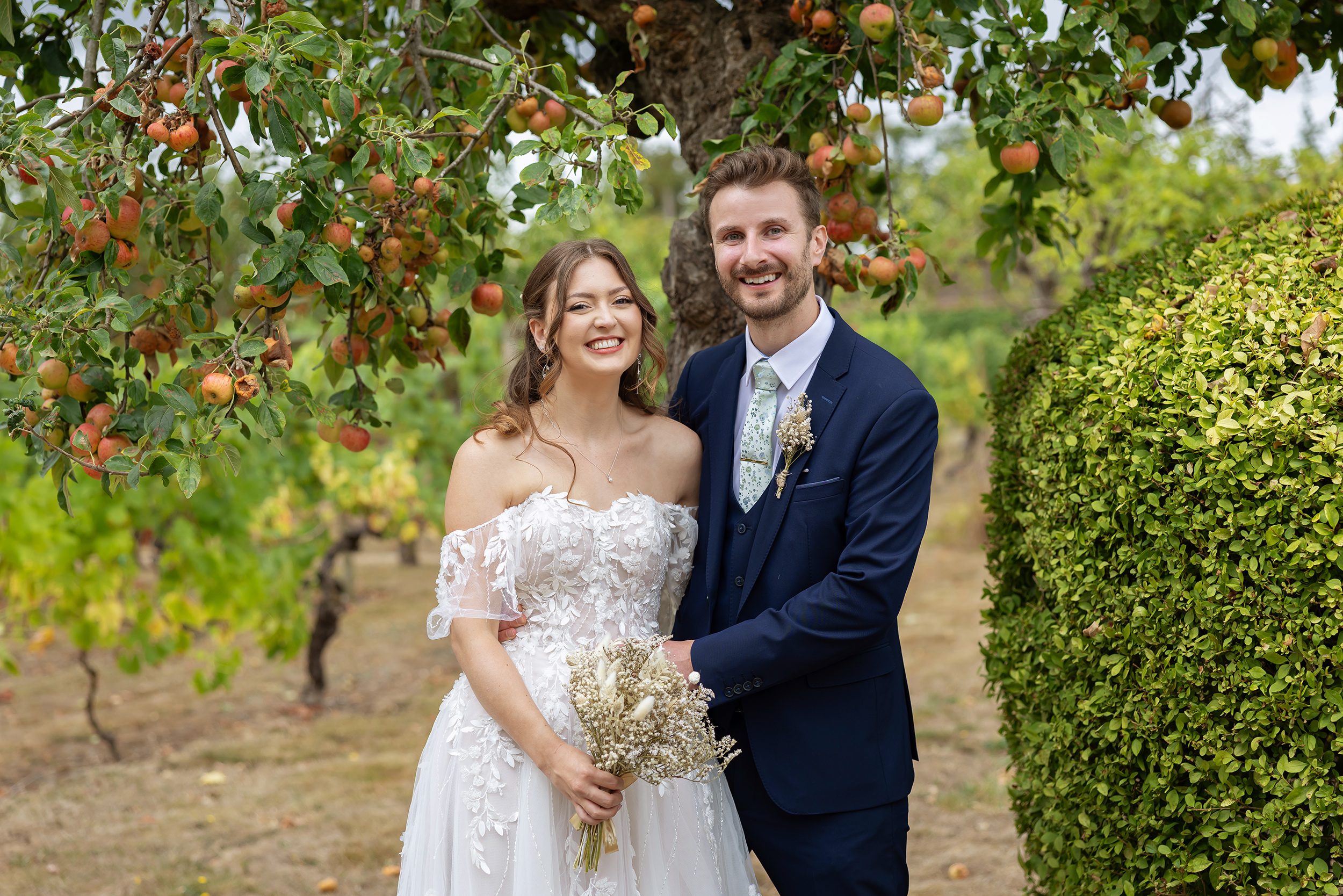 Bride and groom pose by orange tree at Stanlake Park wedding