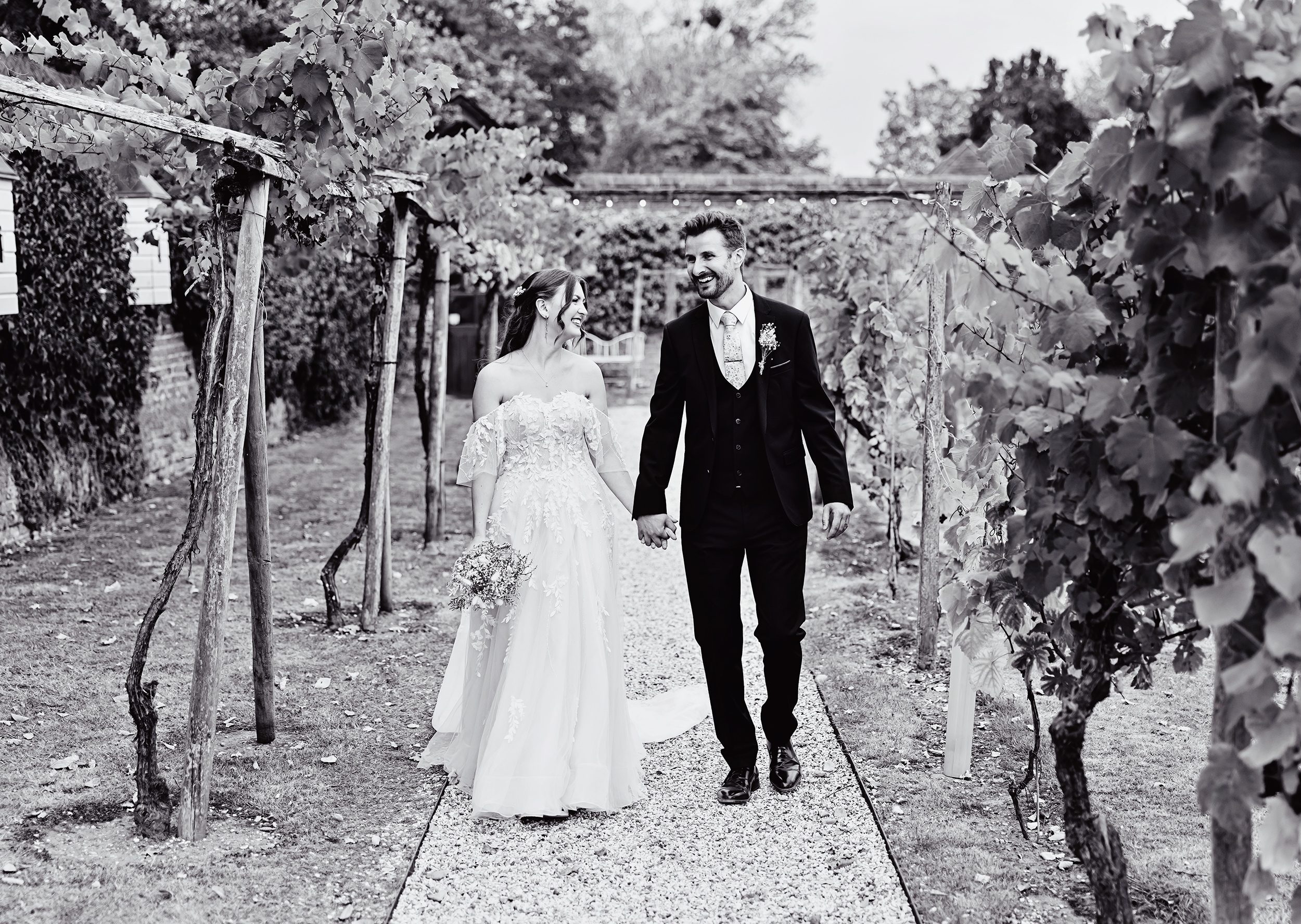 Bride and groom walk through vineyards at Stanlake Park wedding