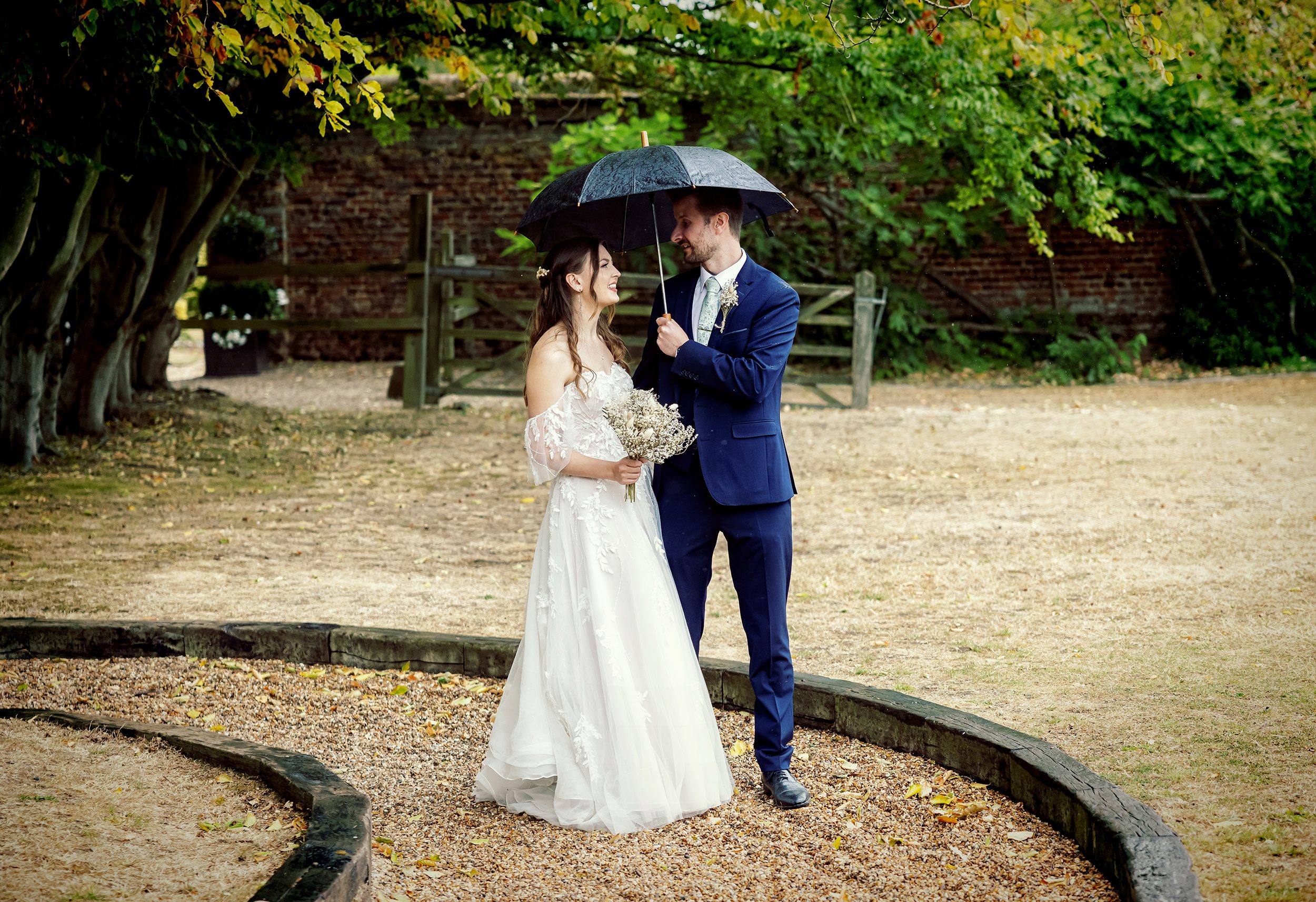 Bride and groom with umbrella at Stanlake Park