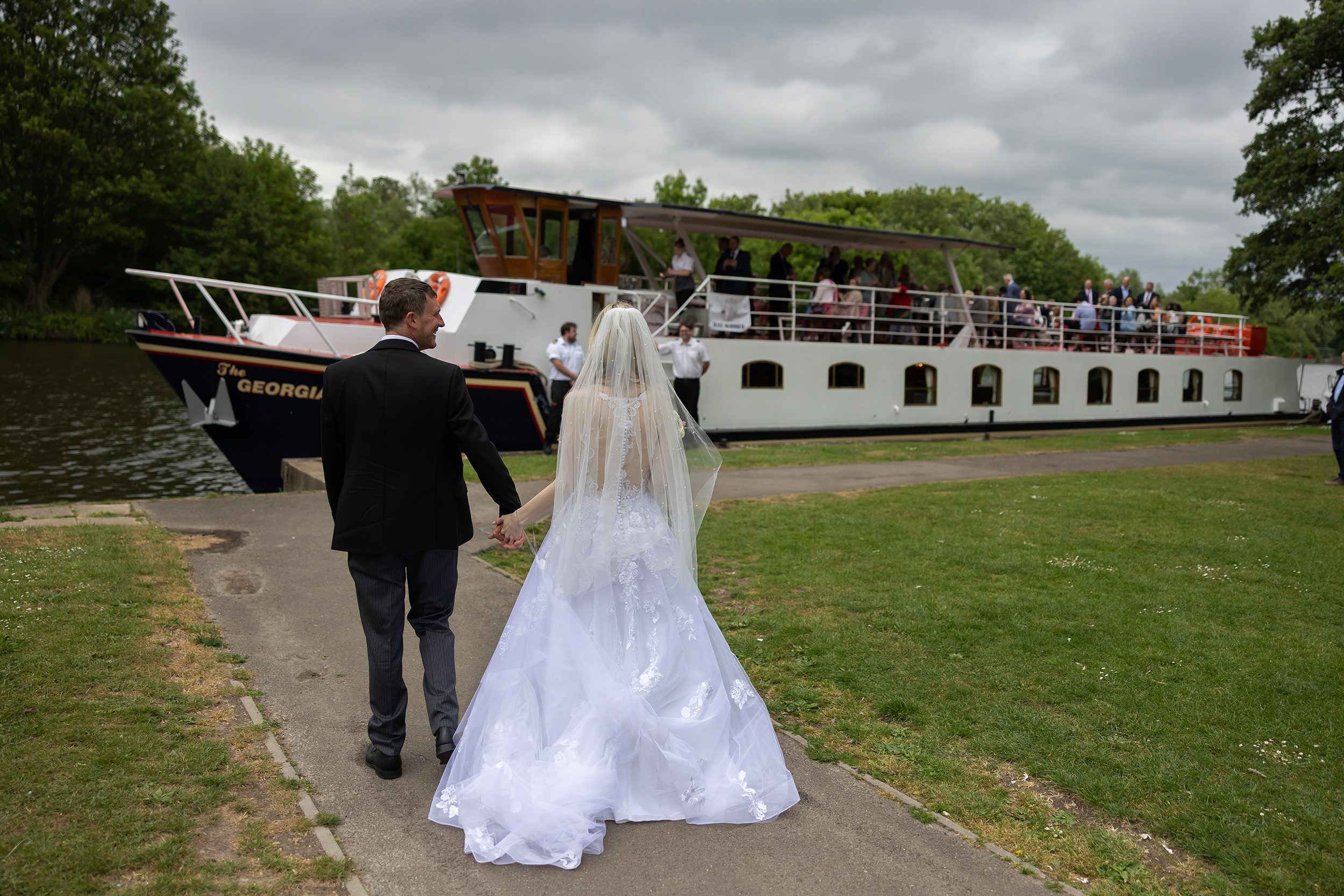 Windsor-wedding-couple-walk-towards-reception-barge-on-Thames