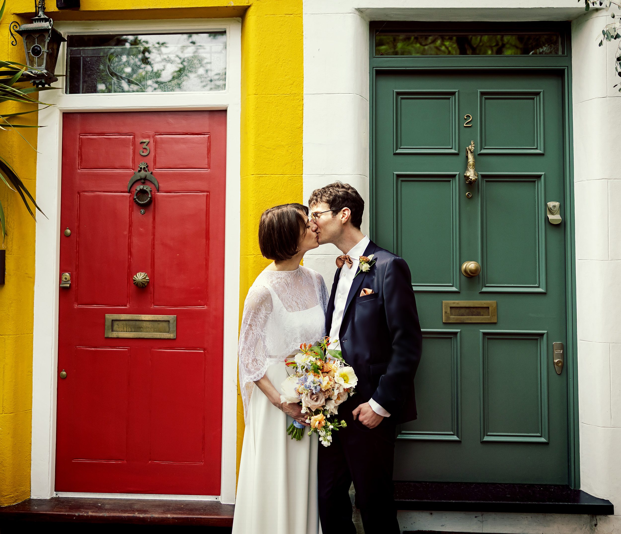 Bride and groom kiss in front of colourful London doors
