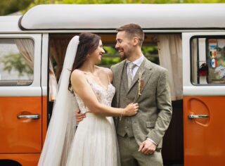 Bride and groom laughing together by VW Camper Van