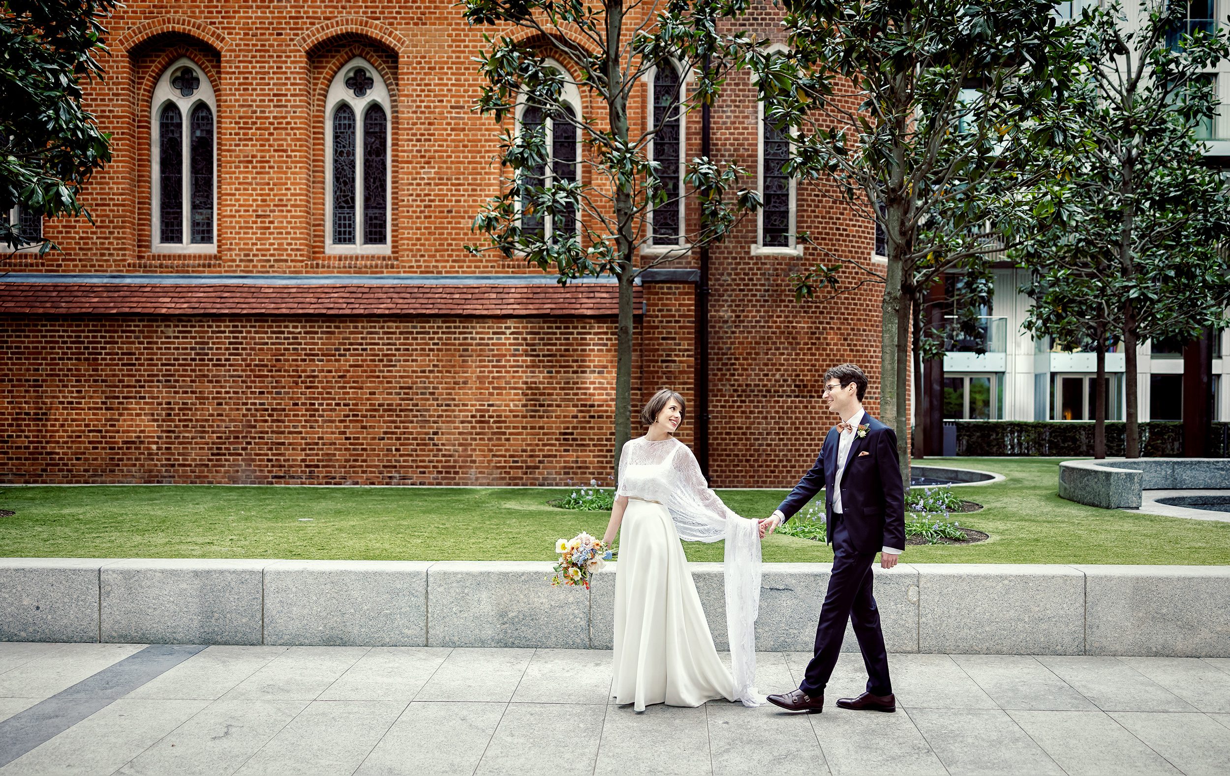 Bride and groom walk past Fitzrovia Chapel after wedding
