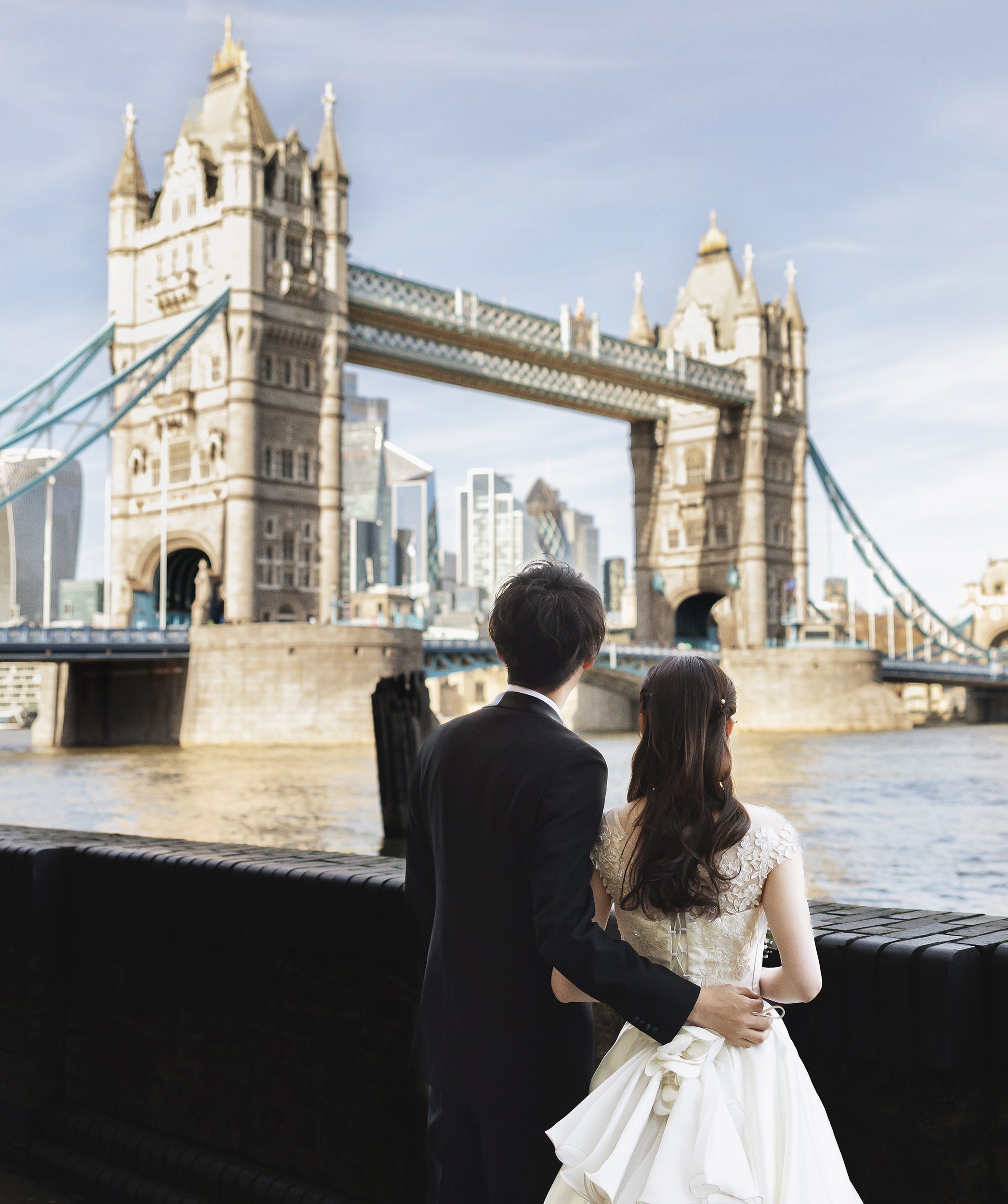 Bride and groom by Thames looking at Tower Bridge