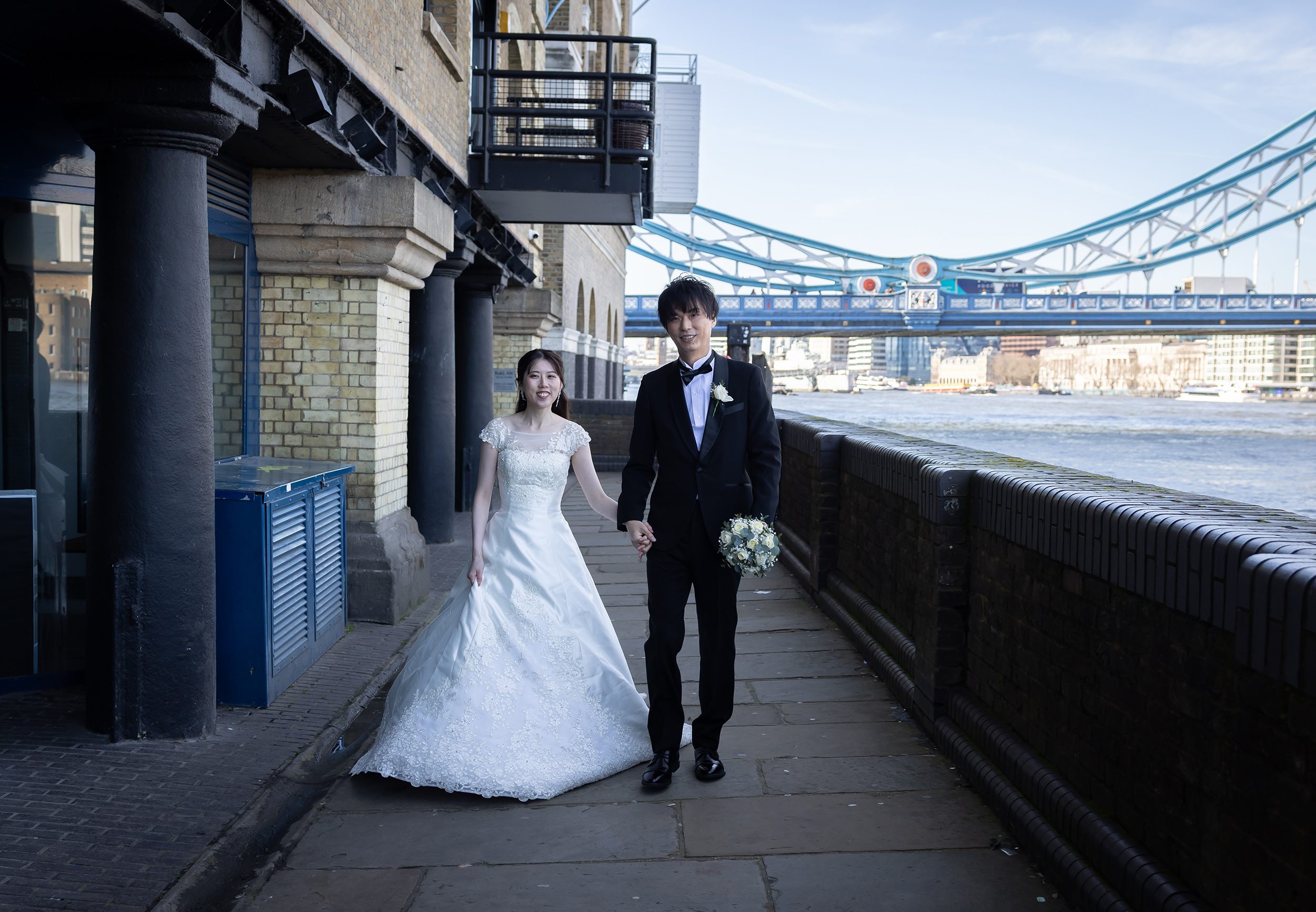 Bride and groom walk together by Tower Bridge
