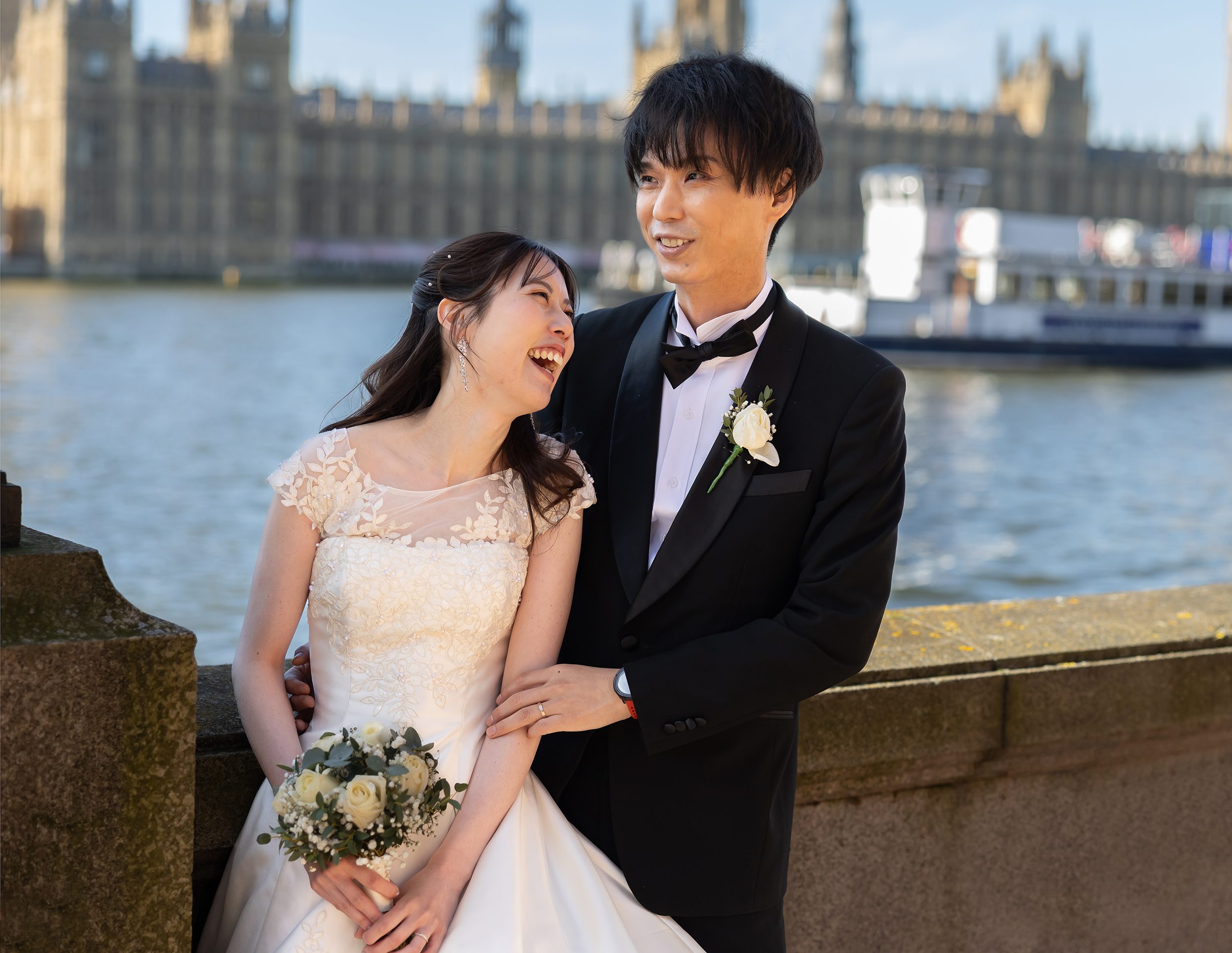 Bride and groom laugh by Houses of Parliament wedding