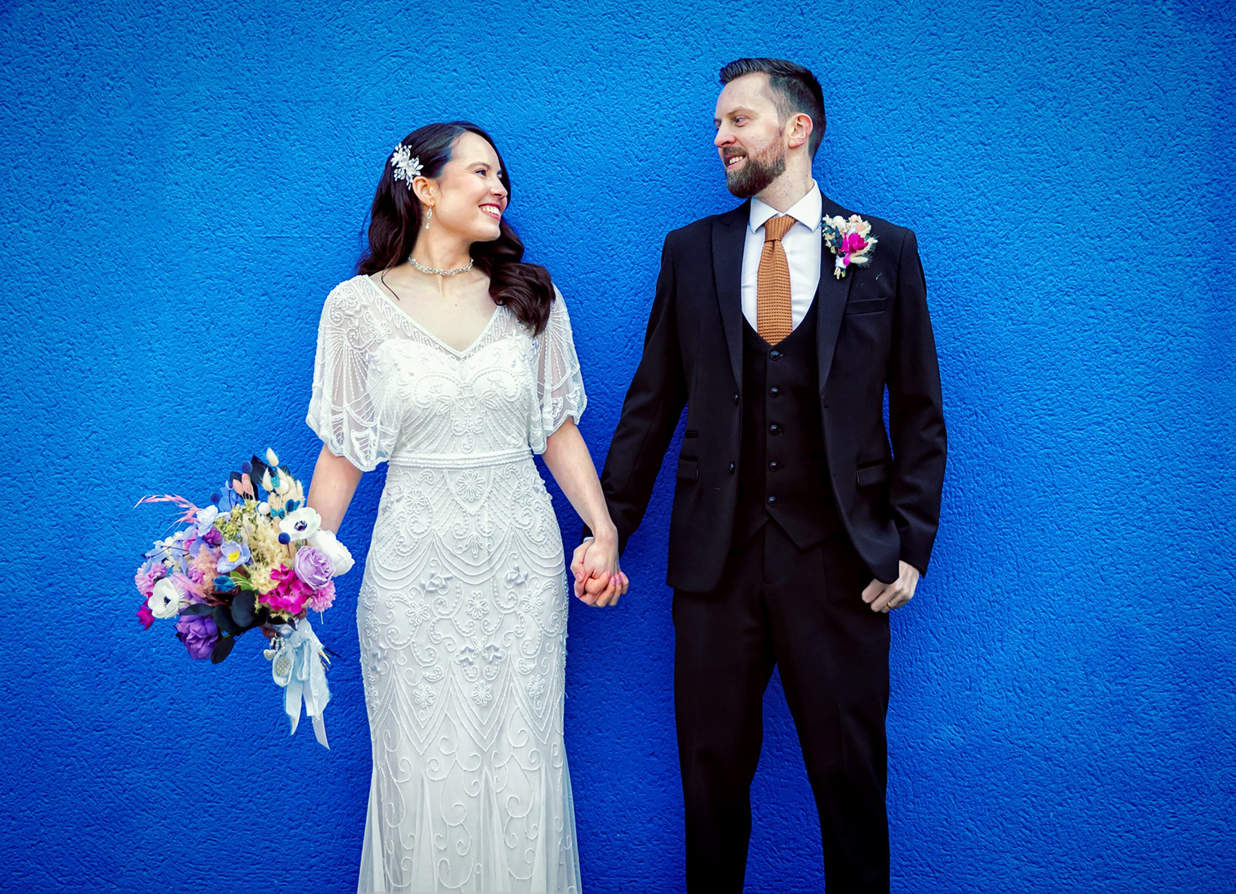 Islington wedding couple holding hands by blue wall Upper Street